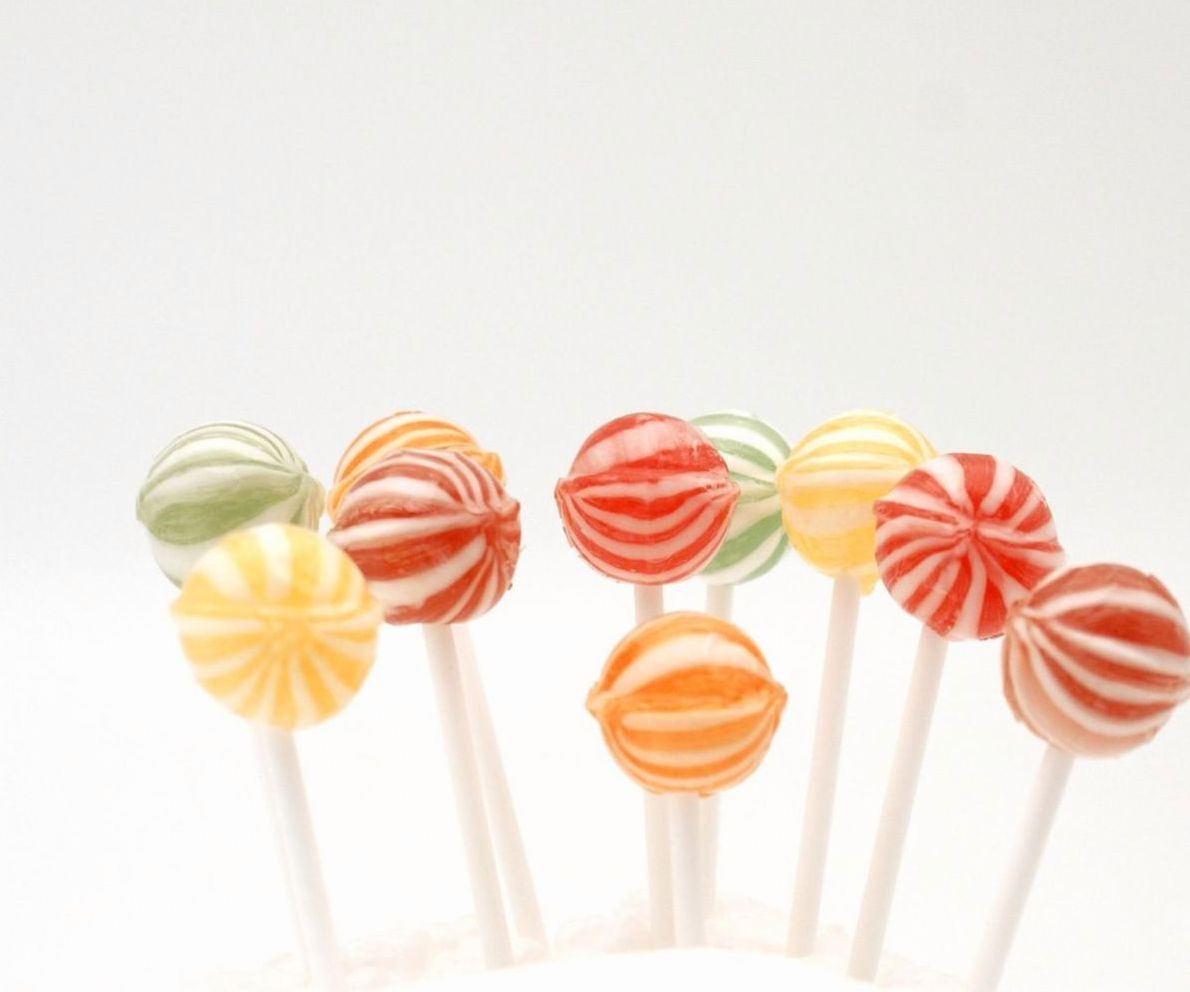 Hands wrapping handmade lollipops on a marble counter